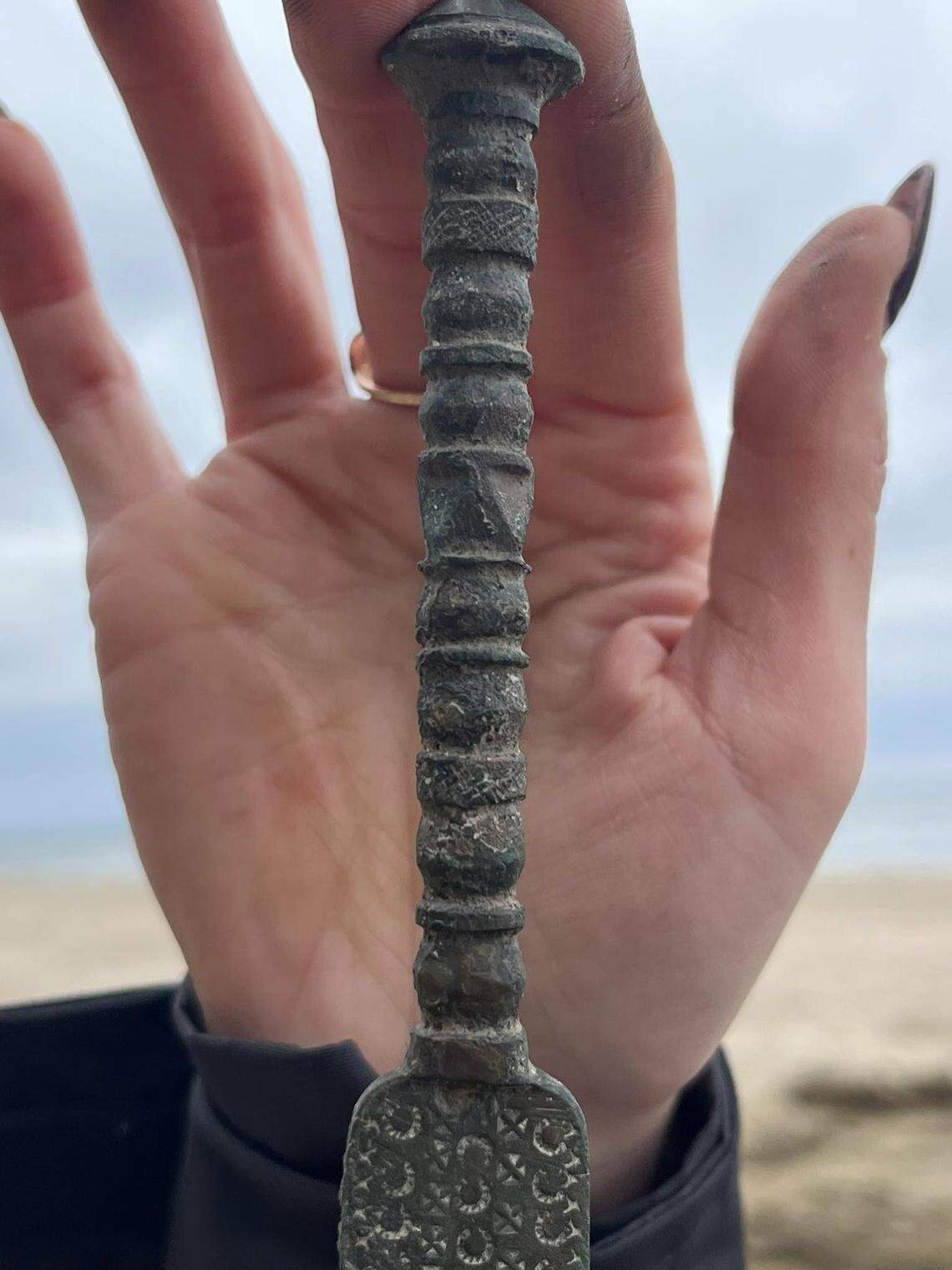 A close-up photo shows the decorated handle of the ancient dagger.