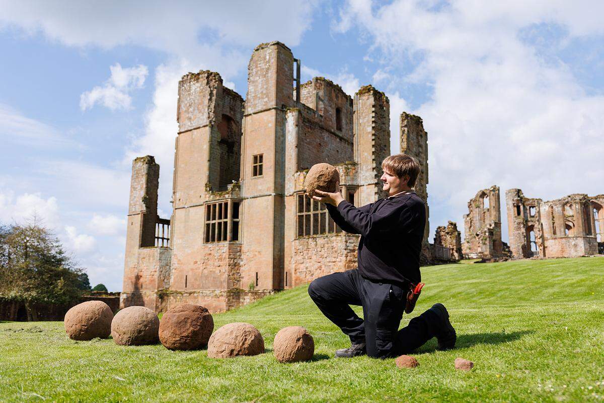 A worker holds up one of the medieval catapult shots.
