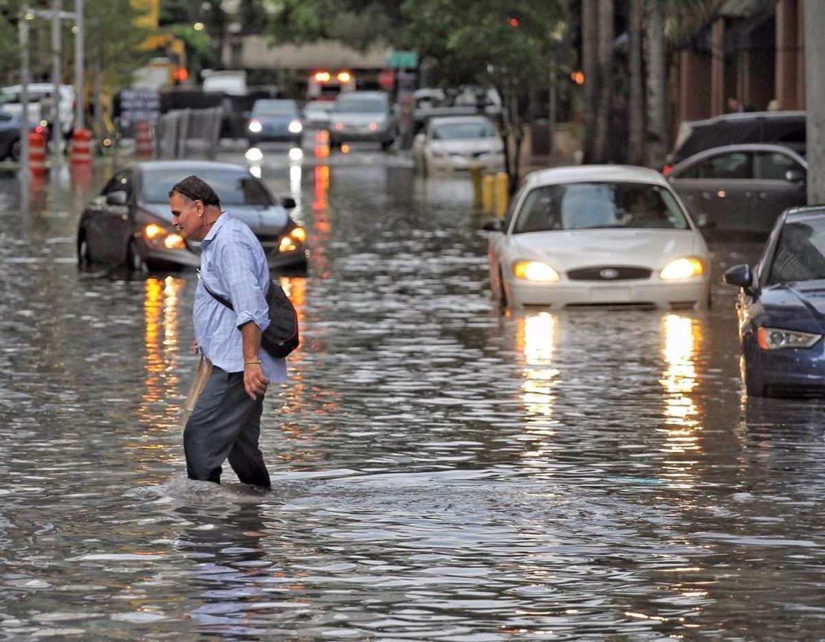 Pedestrians make their way through the flooded streets in the Brickell area of Miami on Aug. 1. Property owners in Miami-Dade, Broward and Palm Beach counties account for 16.5 percent of all flood insurance policies across the country.