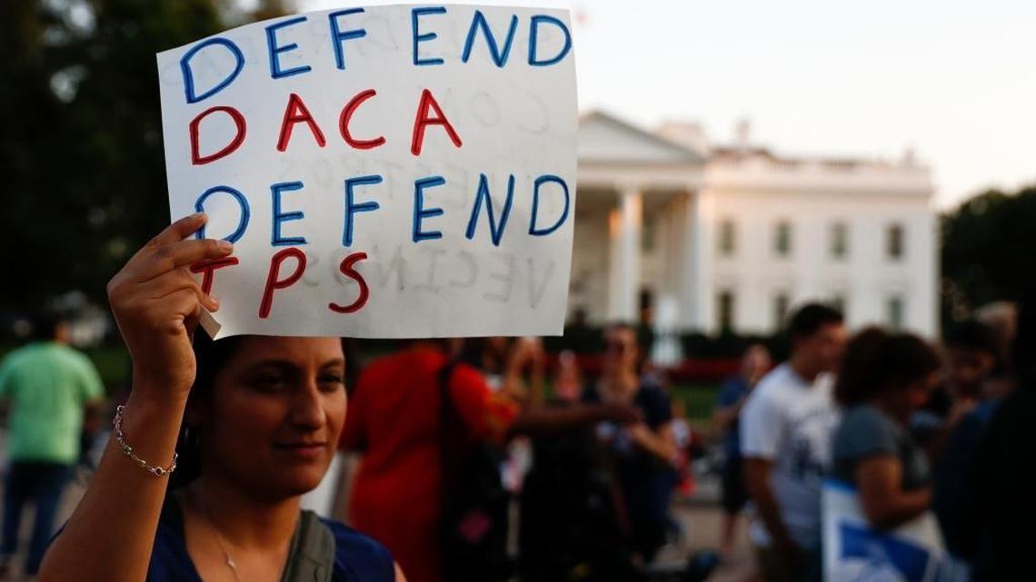 A woman holds up a sign that reads “Defend DACA Defend TPS” during a rally supporting Deferred Action for Childhood Arrivals, or DACA, outside the White House in Washington on Sept. 4, 2017. TPS stands for “Temporary Protected Status.”