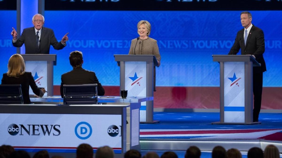Hillary Clinton, former Secretary of State and 2016 Democratic presidential candidate, center, smiles as Senator Bernie Sanders, an independent from Vermont and 2016 Democratic presidential candidate, left, speaks during the Democratic presidential candidate debate with Martin O'Malley, former governor of Maryland and 2016 Democratic presidential candidate, at Saint Anselm College in Manchester, New Hampshire, U.S., on Saturday, Dec. 19, 2015.