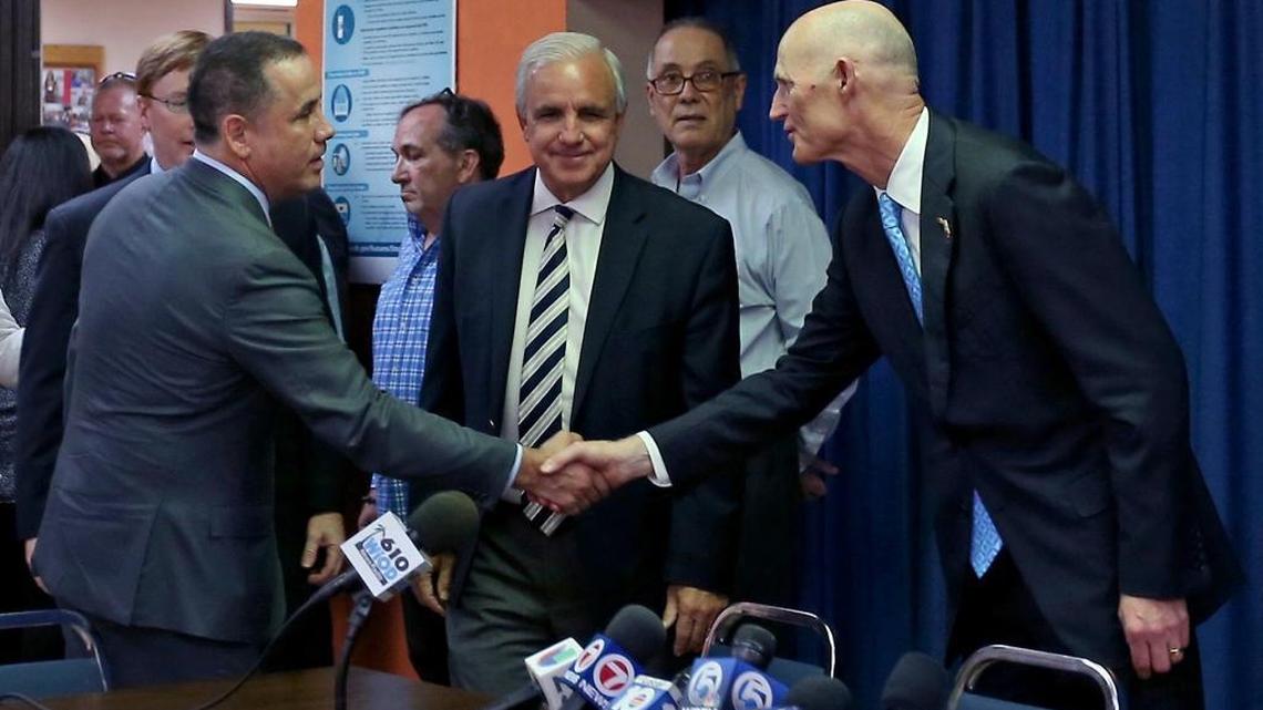 Florida Gov. Rick Scott, right, reaches to shake hands with Miami Beach Mayor Philip Levine as Miami-Dade Mayor Carlos Gimenez looks on prior to a roundtable about the Zika virus at the De Hostos Senior Center in Wynwood.