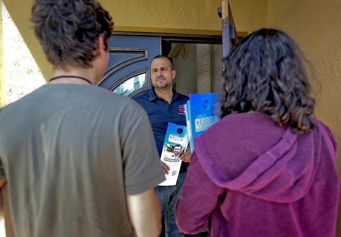 Carlos Caballero, 15, and Sajira Guevara, 17, go door to door in West Kendall, asking people like Yaniel Martinez about Republican Rep. Carlos Curbelo.