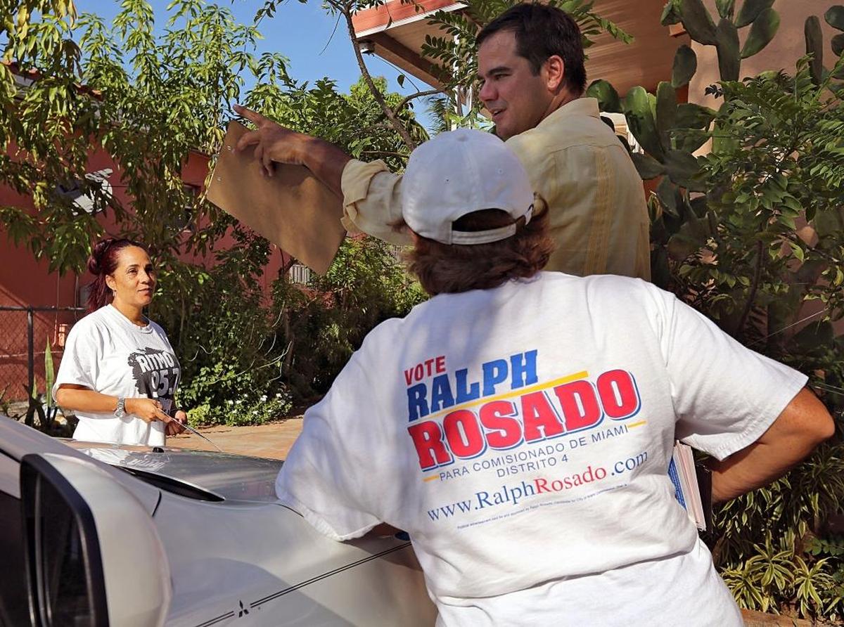Resident Silvia Herrera, left, takes a moment to talk with Ralph Rosado, who is campaigning for Miami’s District 4 commission seat, along with campaign volunteer, Sara Noboa, right around the Magic City neighborhood.