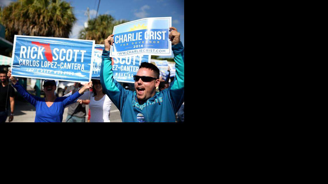 
Supporters for both Gov. Rick Scott and candidate Charlie Crist hold up signs as a bus carrying former Gov. Crist passes by on Monday, Nov. 3, 2014 in Miami.
