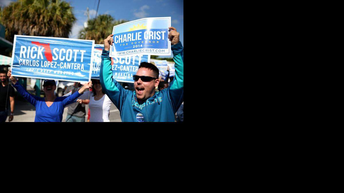 
Supporters for both Gov. Rick Scott and candidate Charlie Crist hold up signs as a bus carrying former Gov. Crist passes by on Monday, Nov. 3, 2014 in Miami.
