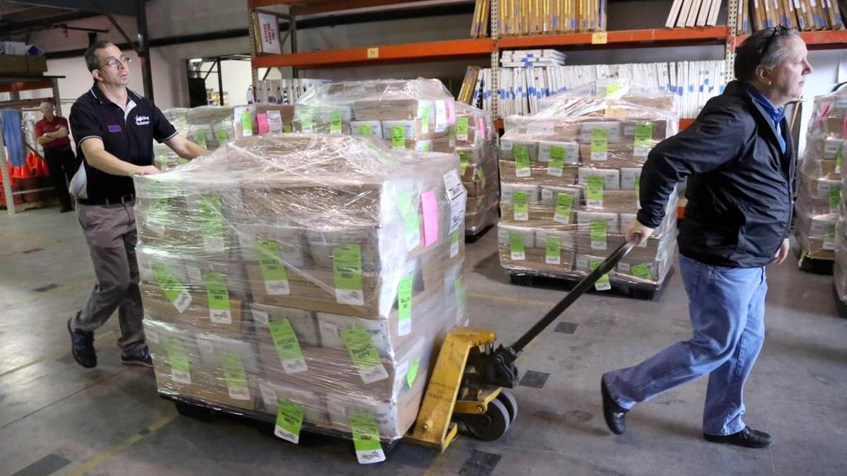 Matt Parri, left, and Martin Munro, with the Pinellas County Supervisor of Elections Office, move one of 18 pallets of absentee ballots to a delivery truck at the warehouse in Largo on Feb. 9.