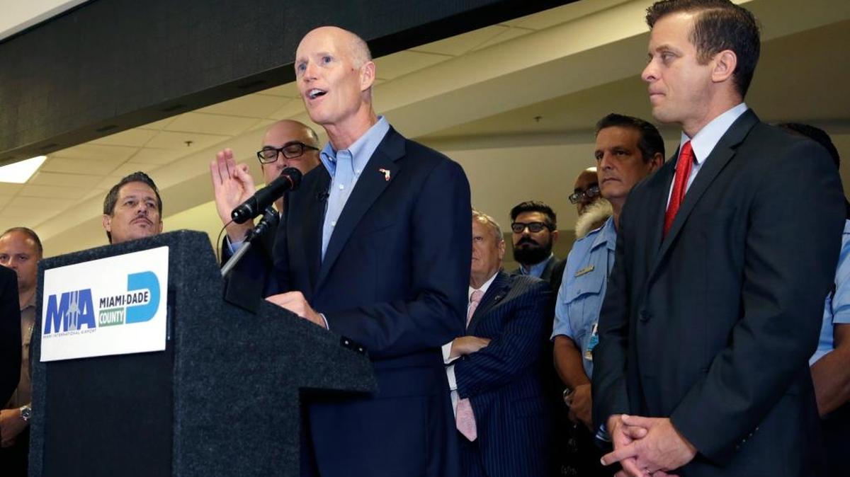 
Florida Gov. Rick Scott, left, speaks as Lt. Gov. Carlos Lopez-Cantera, right, listens during a news conference at Miami International Airport, Wednesday, to highlight record tourism numbers for the state.
