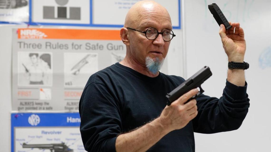Mike Weinstein, director of training and security at the National Armory gun store and gun range, holds up a Glock 9mm hand gun during a Concealed Weapons Permit class, Tuesday, Jan. 5, 2016, in Pompano Beach, Fla.