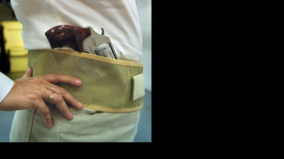 A woman wears a Smith & Wesson pistol in a belly band, which can be worn under the shirt to hold a concealed weapon.

