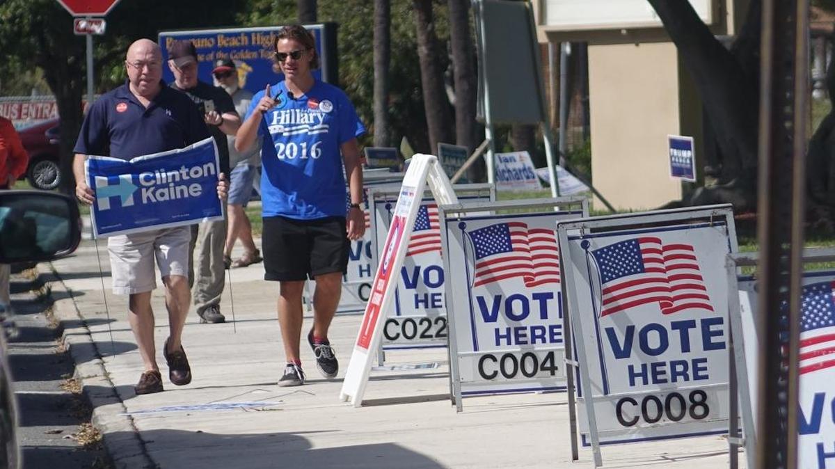 Hillary Clinton supporters carry signs, Tuesday, Nov. 8, 2016, at the polling places at the Emma Lou Olson Civic Center in Pompano Beach.