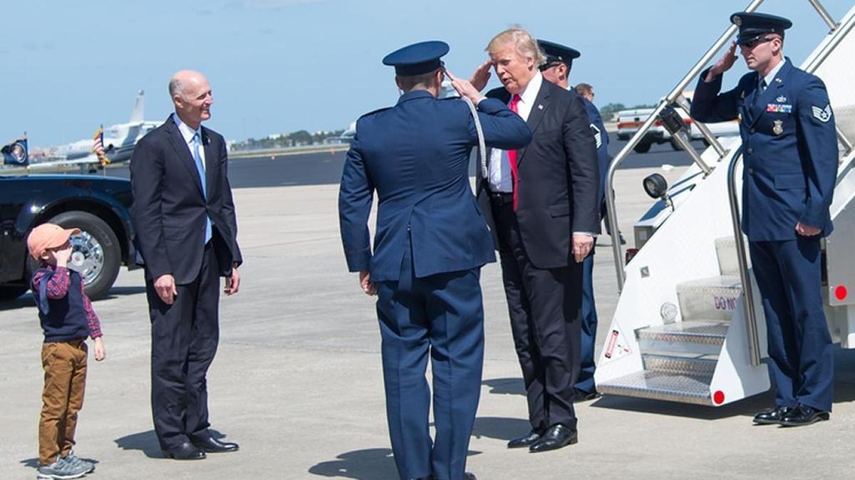 Florida Gov. Rick Scott, with grandson Auguste at his side, greets President Donald Trump as he deplanes Air Force One in Orlando