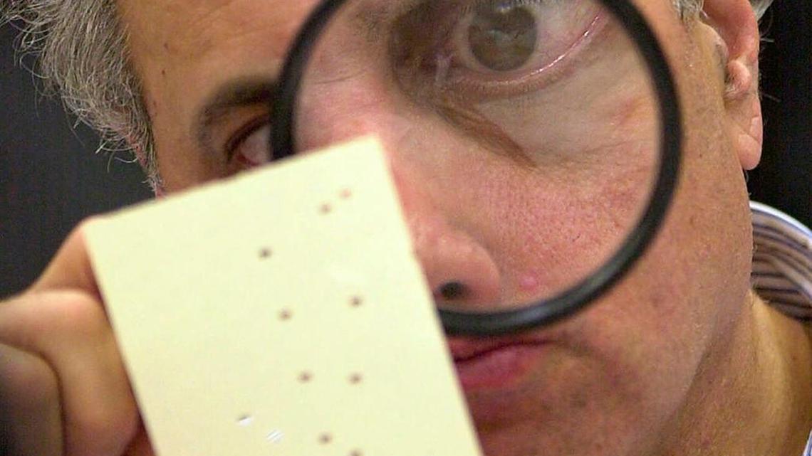 Broward County canvassing board member Judge Robert Rosenberg uses a magnifying glass to examine a disputed ballot at the County Courthouse in Fort Lauderdale, Nov. 24, 2000.