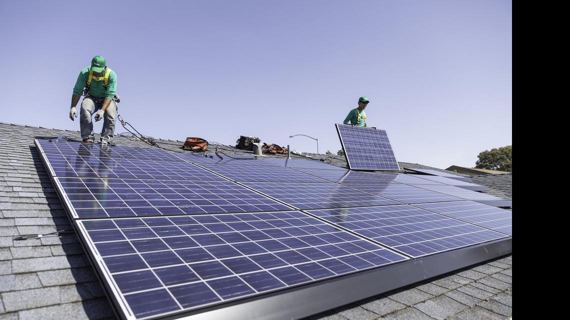 
Workers install solar panels on the roof of a home. 
