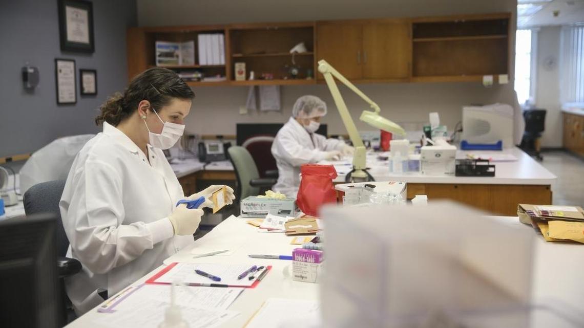 Crime laboratory analysts Carolyn Krieger (front left) and Jared Baum work in a DNA lab at the FDLE’s facility in Tampa, on Sept. 10, 2015. Florida's law enforcement agencies have been facing burgeoning financial troubles, making it harder for them to retain employees and slowing their ability to process evidence.