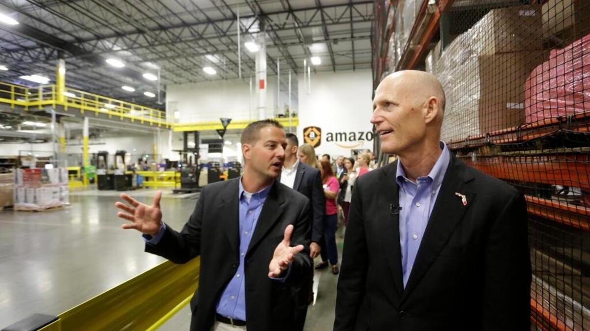 Chris Monnot, left, general manager of the Amazon fulfillment cente, gives Gov. Rick Scott, right, a tour of his facility on Oct. 28 in Lakeland.