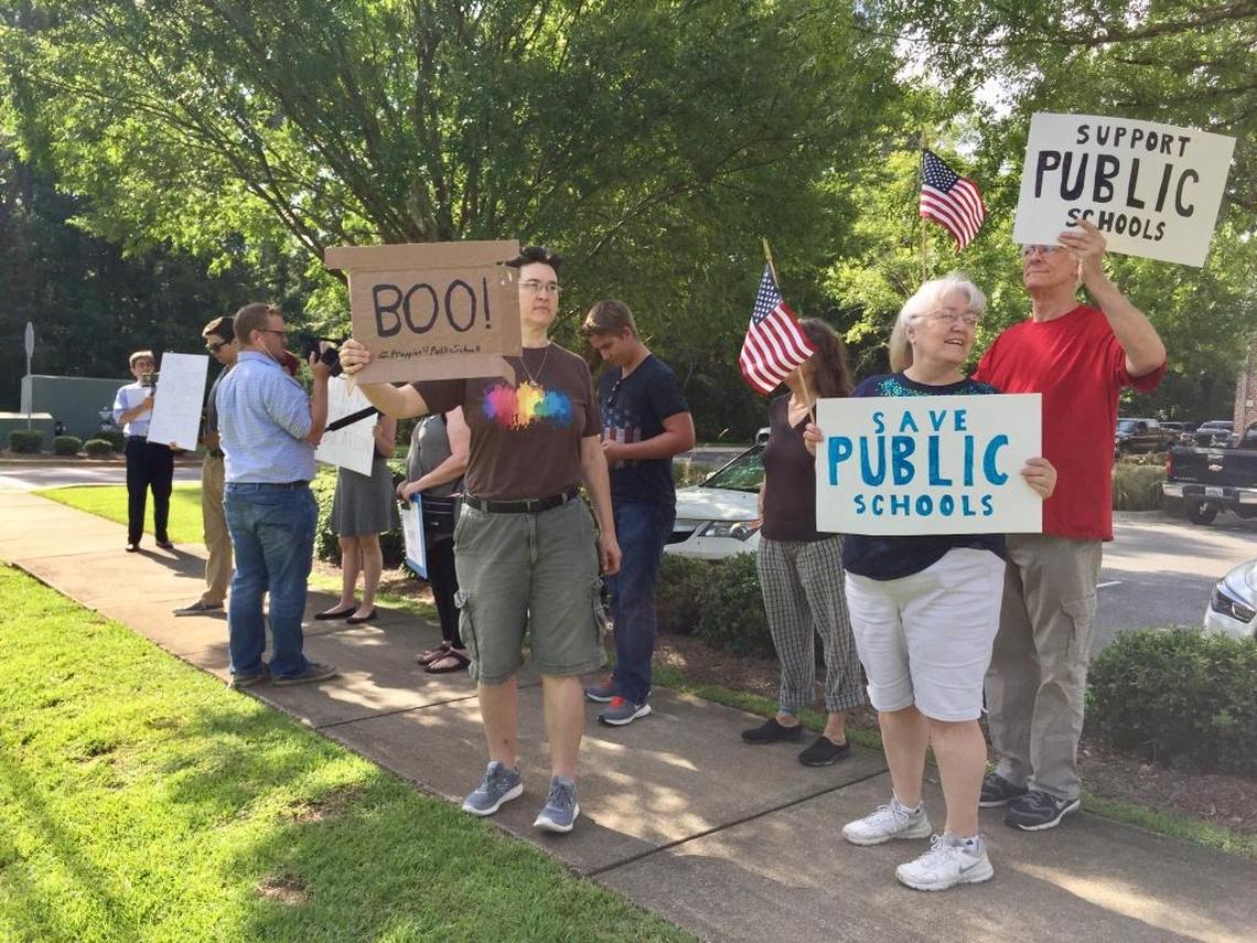 A dozen protesters, including Tallahassee residents Colleen and Al Thorburn, far right, gathered outside Holy Comforter Episcopal School in Tallahassee to greet U.S. Education Secretary Betsy DeVos on Tuesday, Aug. 29, 2017. DeVos spent two hours visiting classrooms at the private Christian school.
