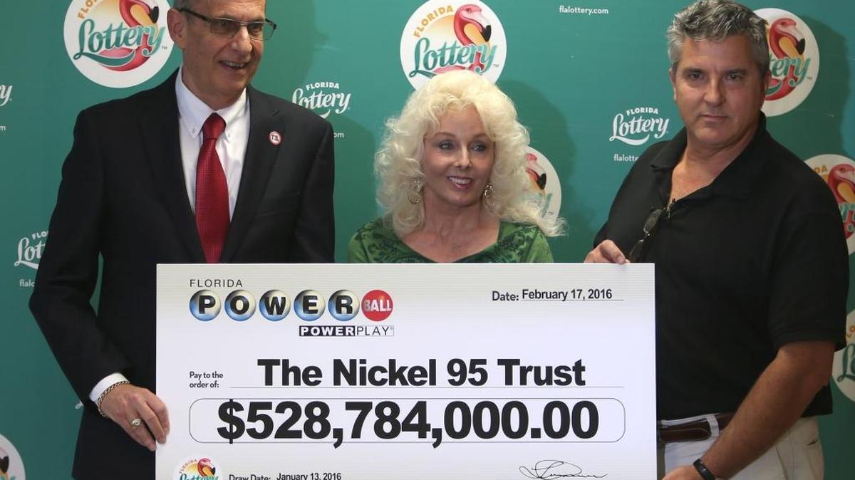 Florida Lottery Secretary Tom Delacenserie, left, is resigning June 2. He’s shown here in 2016 presenting Maureen Smith and David Kaltschmidt with their one-third share of the Jan. 13, 2016, world- record Powerball jackpot in Tallahassee, Fla. (AP Photo/Steve Cannon)