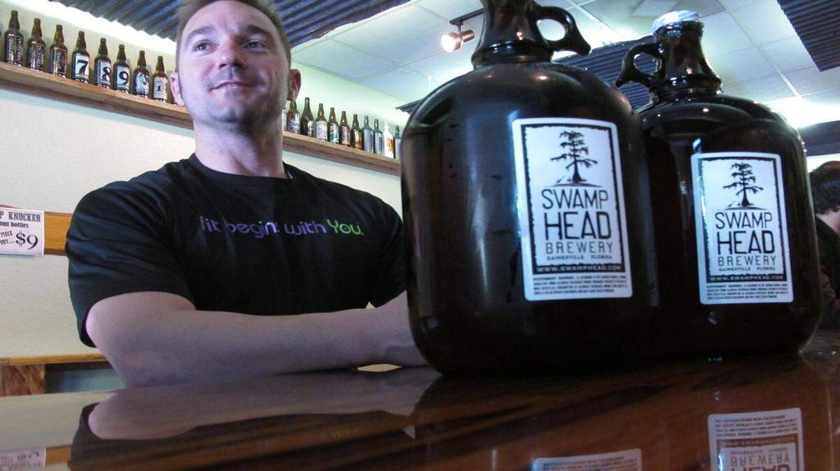 
In this Friday, March 29, 2013 file photo, patron Adam Rudell, of St. Petersburg, Fla., sits with two gallon-sized jugs of beer, known among beer enthusiasts as growlers, at the Swamp Head Brewery in Gainesville, Fla.

