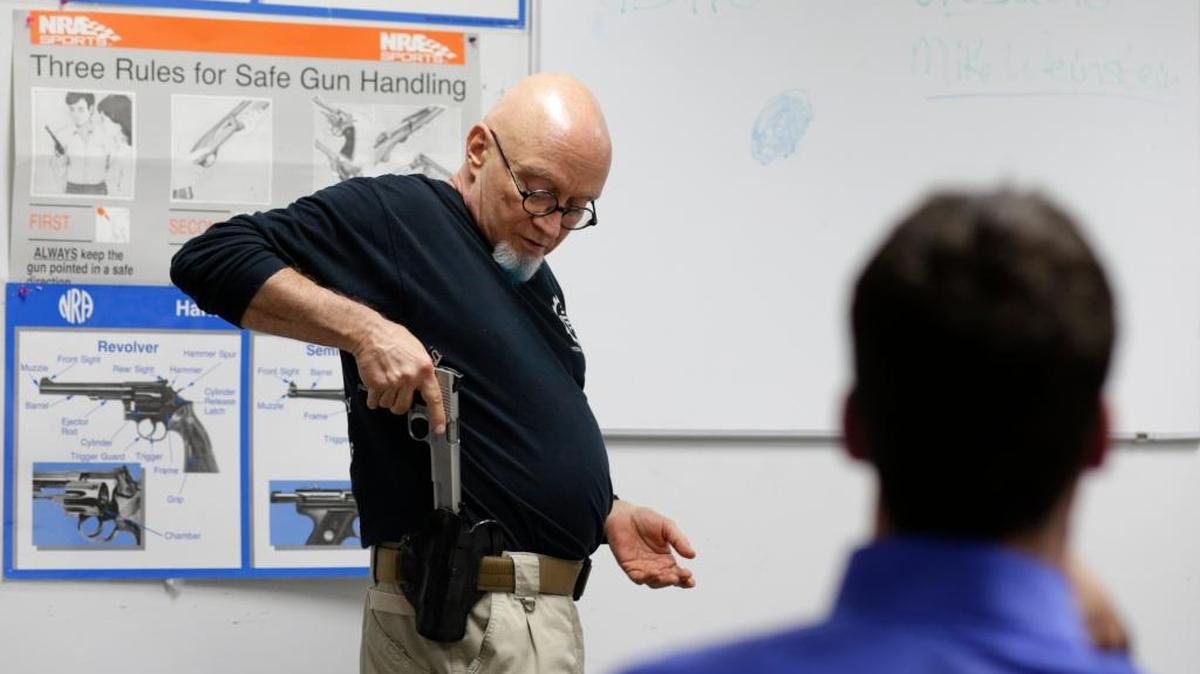 Mike Weinstein, director of training and security at the National Armory gun store and gun range, shows how to safely put a Ruger 1911 handgun in and out of a holster during a Concealed Weapons Permit class, Tuesday, Jan. 5, 2016, in Pompano Beach, Fla.