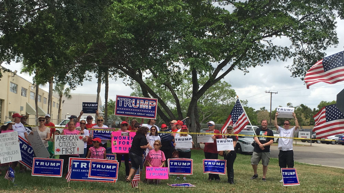 Trump supporters wave flags and signs at passing drivers in Miami Lakes.