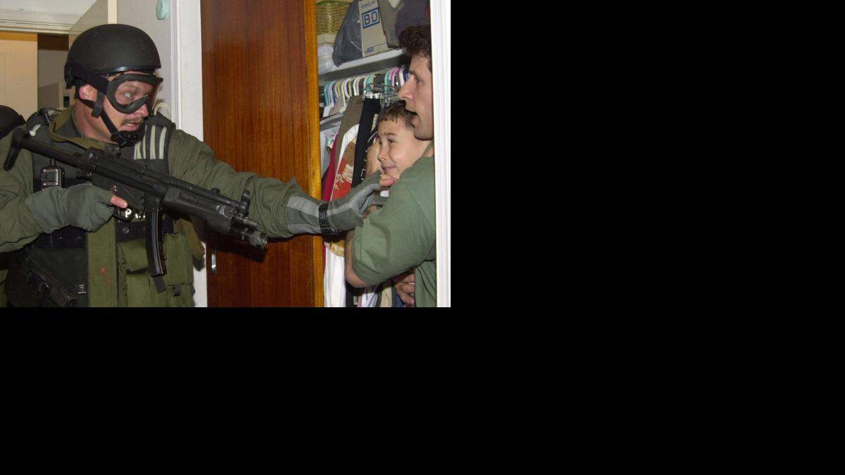 
Elián González is held in a closet by Donato Dalrymple, right, as government officials search the home of Lázaro González for the young boy on April 22, 2000.
