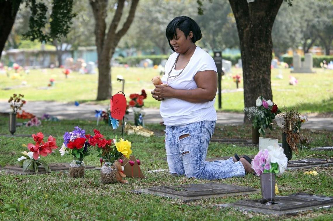 Shakila Stewart holds a small teddy bear as she visits the grave sites of her husband, Maurice Harris Sr., and her son, Maurice Jr. Her husband was killed in a home invasion; her son, gunned down in the street. The two are buried in the Resurrection section at Caballero Rivero Dade North cemetery.