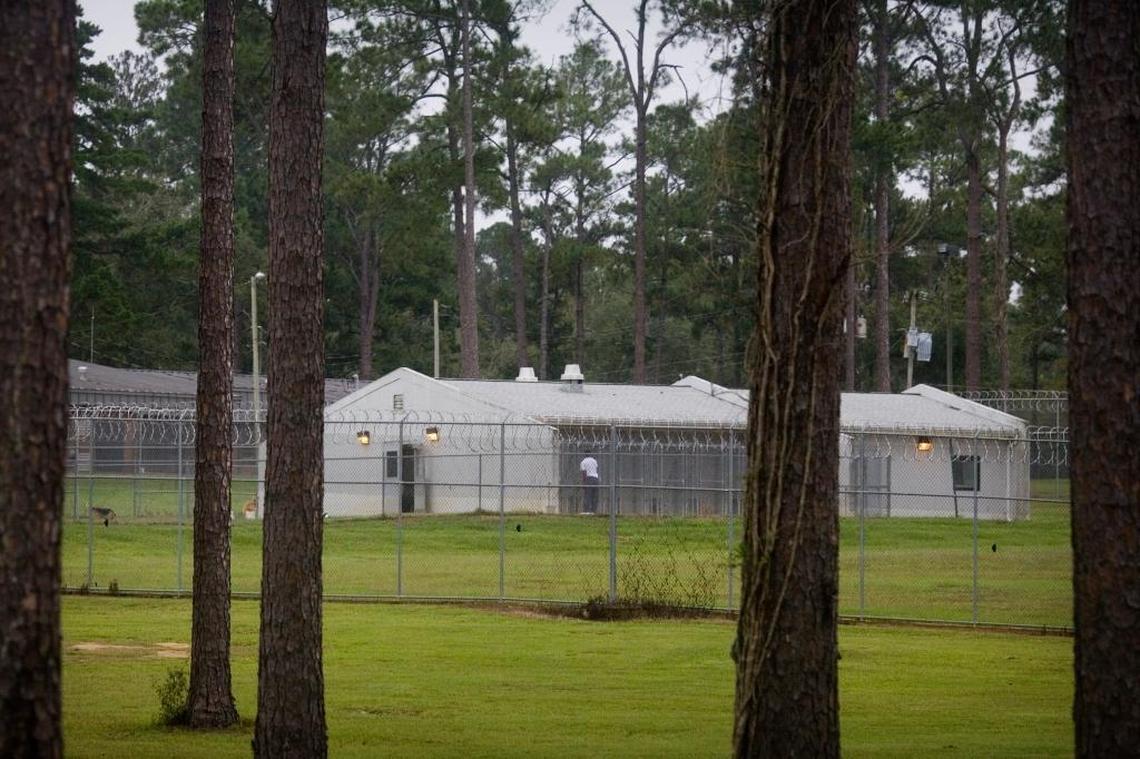 Seen from a distance through the window of a moving van, an inmate at the Arthur G. Dozier School for Boys tends to the school’s kennels on Oct. 13, 2009.