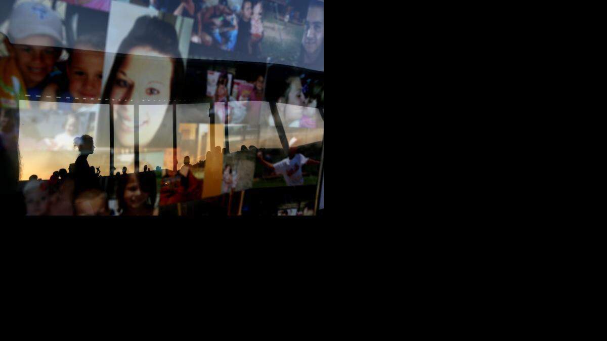 
Mourners are reflected in a framed collage of images featuring Sarah Spirit and her children during a candlelight vigil at Bell Elementary for the victims of Thursday's shootings on Sunday, Sept. 21, 2014 in Bell, Fla.
