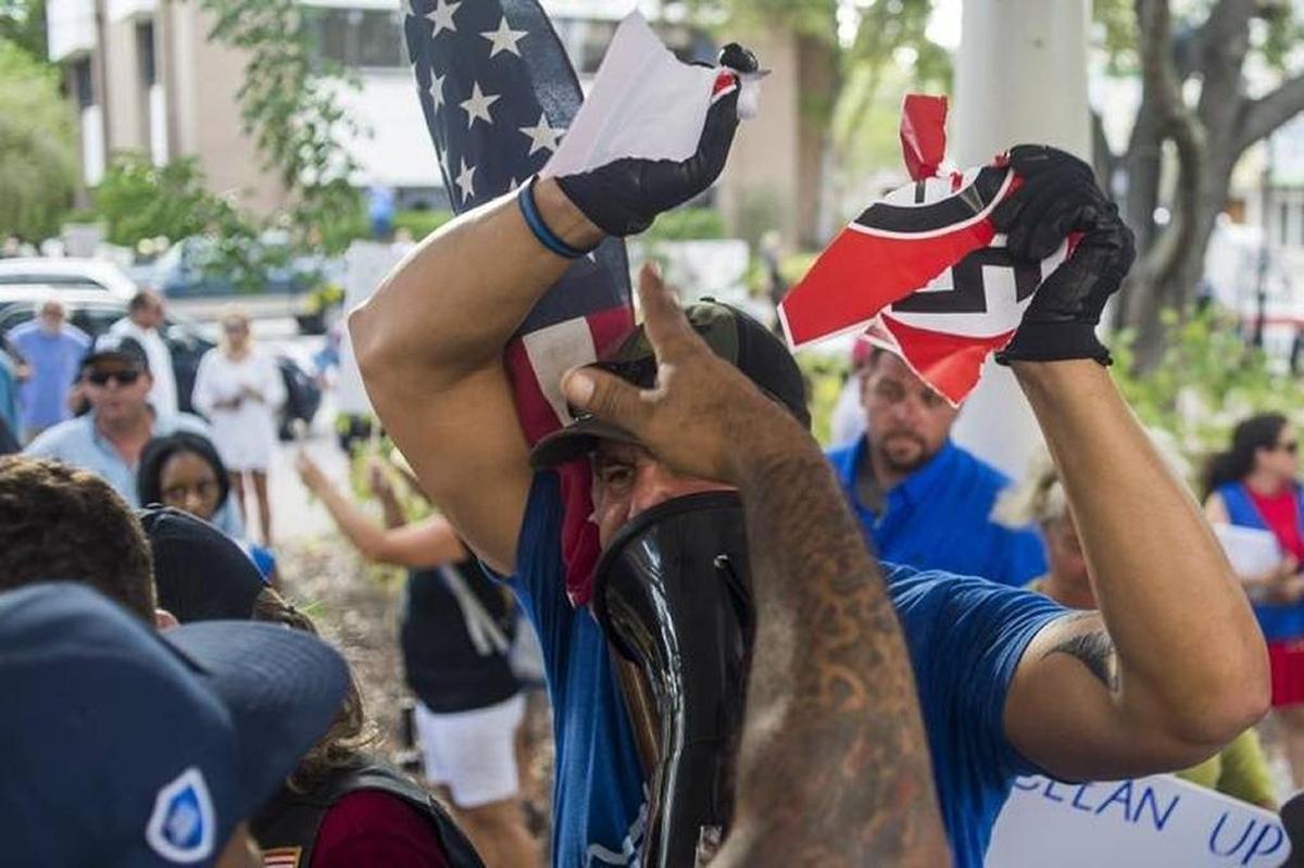 A pro-monument supporter tears up an “Anti-Facist/Nazi” flag as he argues with anti-monument protesters over removal of the Confederate monument in front of the Manatee County Historic Courthouse on Monday evening in downtown Bradenton.