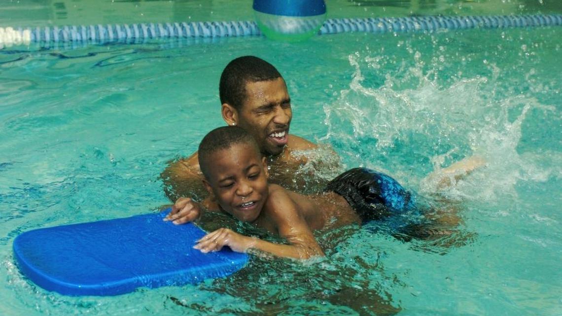 USA Swimmer Cullen Jones helps Tavion Traynham with the kickboard while giving swim lessons to six 8-year-olds in Omaha in 2008. USA Swimming hopes the learn-to-swim program will strengthen efforts to lower minority drowning rates and draw more blacks into the sport.
