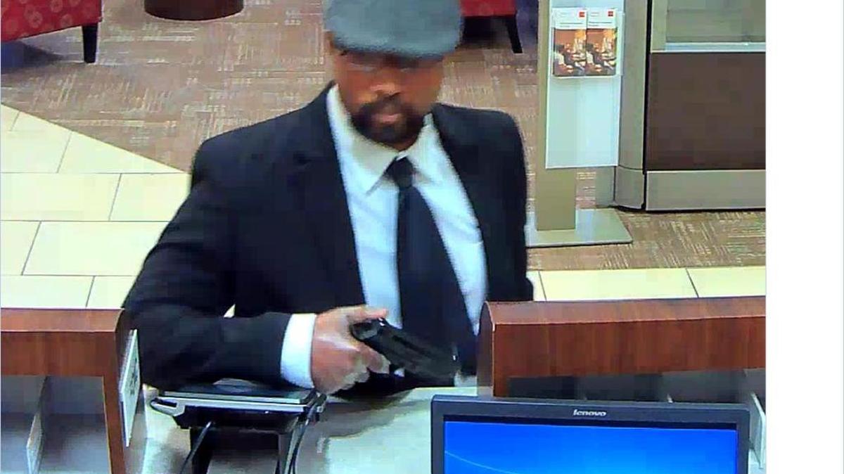 The “Business Bandit” shows a gun during Friday’s robbery of a Wells Fargo branch.
