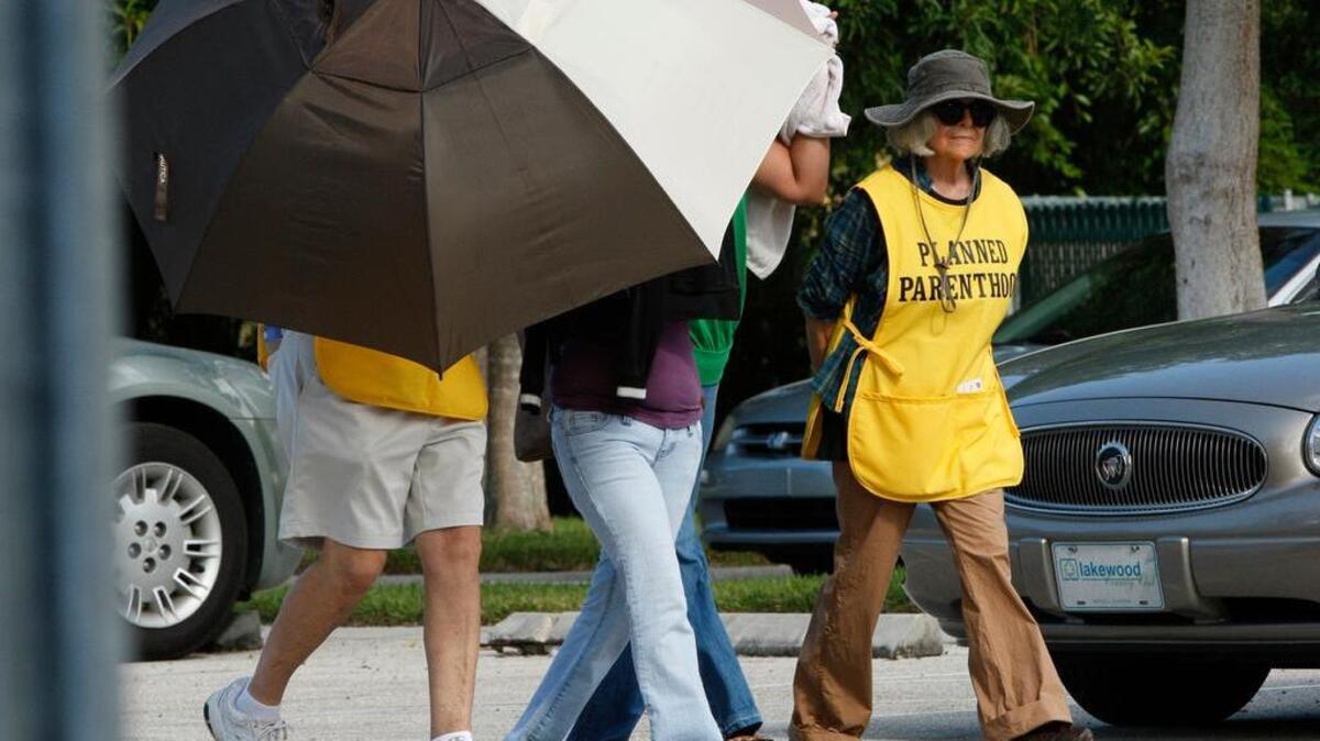 
In this Sept. 14, 2009, file photo, women are concealed from view by Planned Parenthood volunteers as they enter the Planned Parenthood of Collier County in Naples. 
