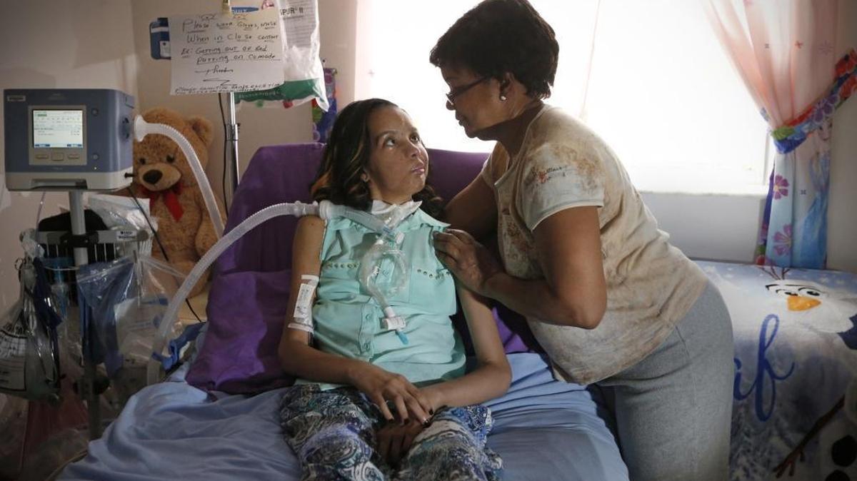 Adriana Parrales, 28, is the lead plaintiff for a disability lawsuit — she and four other plaintiffs are suing Florida’s Agency for Health Care Administration for failing to set standards for home- and community-based services. Parrales has painful tumors on her spine and brain, is confined to her bed and is on a ventilator. Here, Adriana is seen at home with her mother, Rita Parrales, in Miami on Thursday, Oct. 15, 2015.