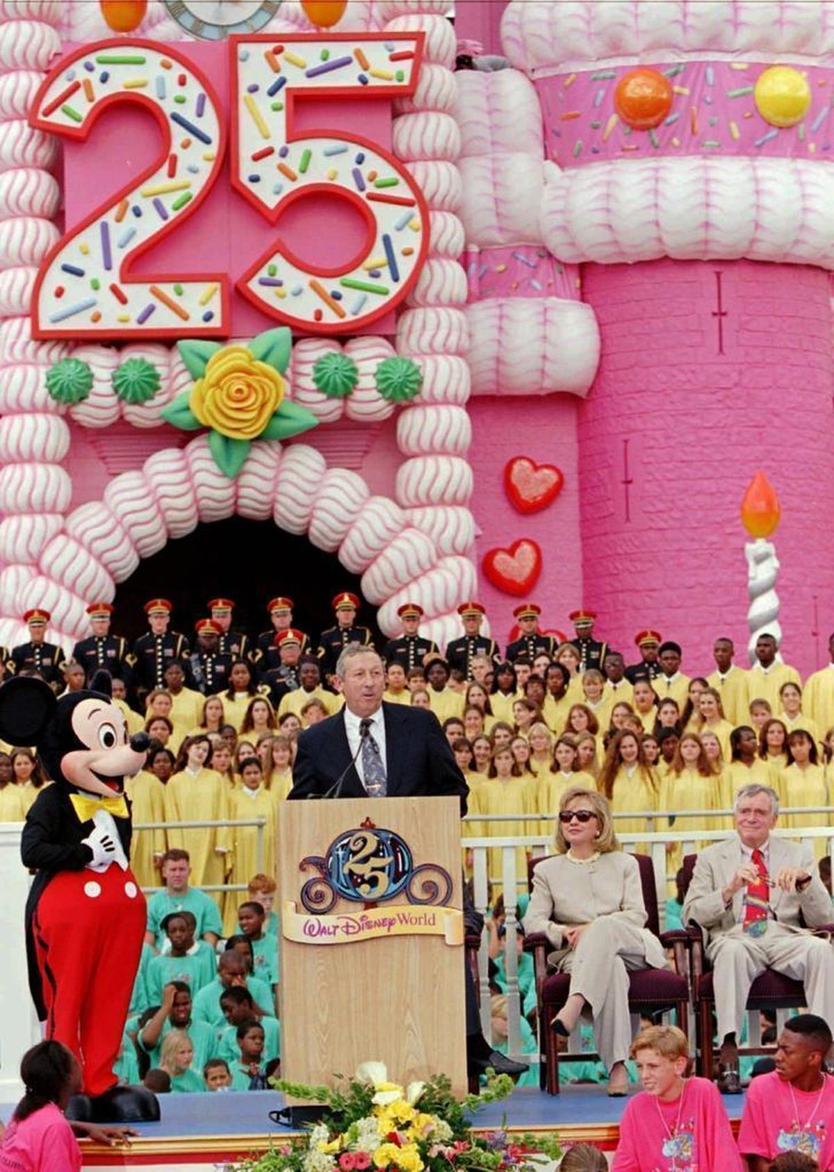 Roy Disney, second from left, nephew of Walt Disney, addresses the crowd along with Mickey Mouse, First Lady Hillary Rodham Clinton, and Fla. Governor Lawton Chiles during the 25th anniversary rededication ceremonies Tuesday, Oct. 1, 1996, at Walt Disney World in Lake Buena Vista, Fla.