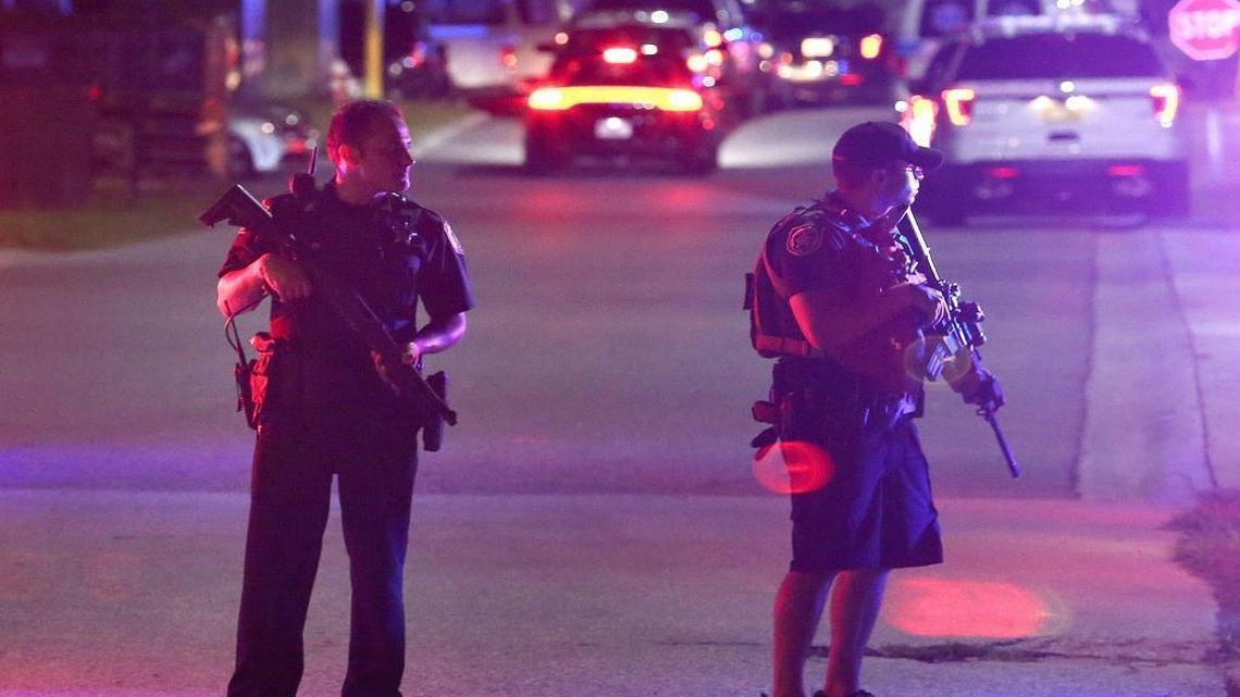 Two law enforcement officers stand guard outside Osceola Regional Medical Center in Kissimmee after two Kissimmee police officers were shot Friday, Aug. 18, 2017, in Kissimmee, Fla. One police officer was shot and killed and another gravely injured by gunfire while checking suspicious people in the central Florida city of Kissimmee, police said early Saturday.