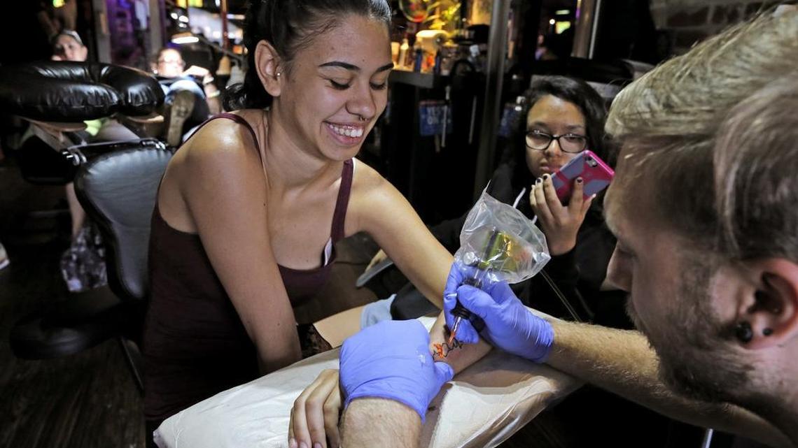 Mitchell Jarrell, right, inks a tattoo on the arm of Lissette Davila, on Saturday, June 18, 2016, in Orlando. Tattoo artists from Stigma Tattoo donated their time and skills as part of a fundraiser to benefit victims of the Pulse nightclub massacre.