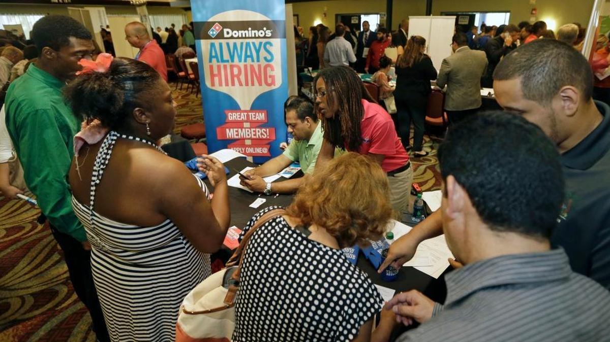 
Job seekers listen as Kaysara Mandry, center, talks about job opportunities at the Domino's booth during a job fair in Miami Lakes, July 15, 2015. 

