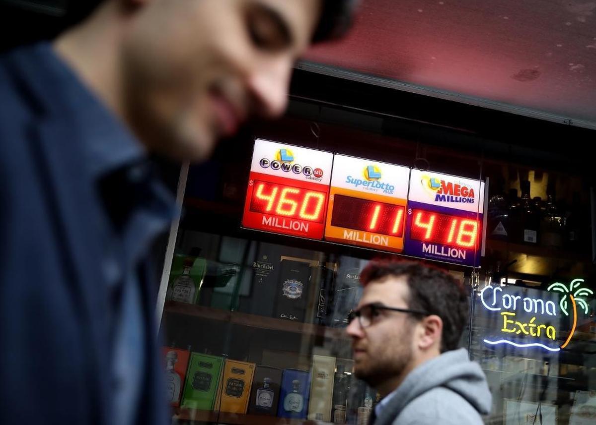 Pedestrians walk by a lottery sign at a convenience store on January 3, 2018, in San Francisco, California. The Powerball jackpot and Mega Millions jackpots are both over $400 million at the same time for the first time. Someone who bought a ticket in Florida won the Mega Millions grand prize, which grew to $450 million, on Jan. 5, 2018.