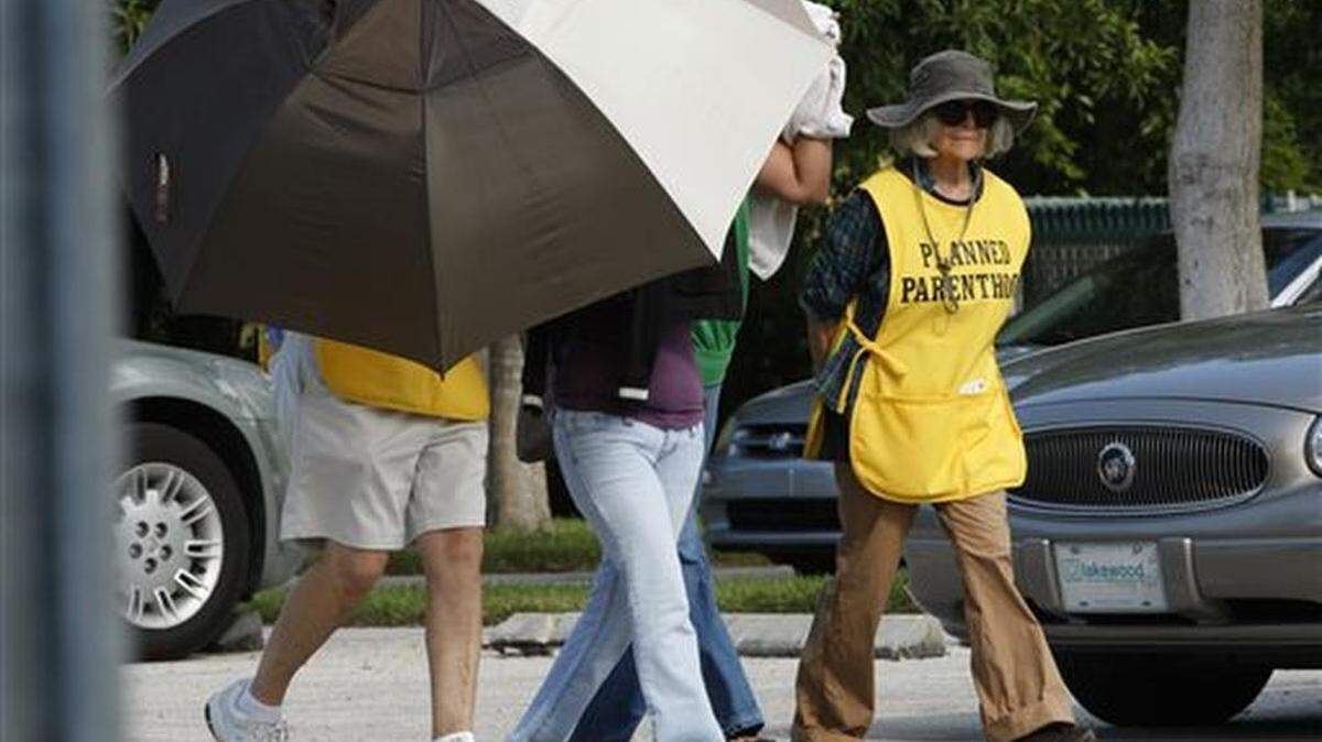 FILE - In this Sept. 14, 2009, file photo, women are concealed from view by Planned Parenthood volunteers as they enter the Planned Parenthood of Collier County in Naples, Fla. Planned Parenthood in Florida asked a judge Monday, Aug. 17, 2015, for an emergency ruling to allow them to continue performing abortions at 12 and 13 weeks after a discrepancy with the state about what constitutes first and second-trimester abortions.