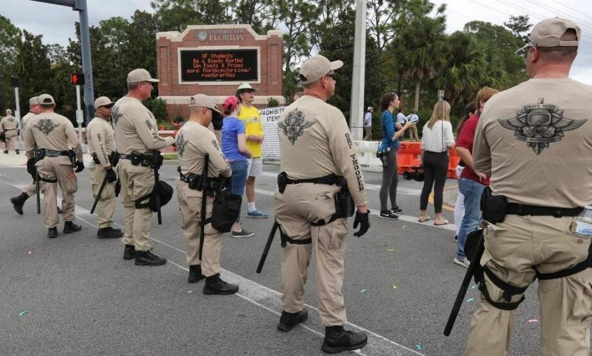 Florida Highway Patrol troopers stand ready at the entrance to University of Florida in Gainesville as hundreds of protesters march near the Phillips Center, where Richard Spencer was allowed to speak.
