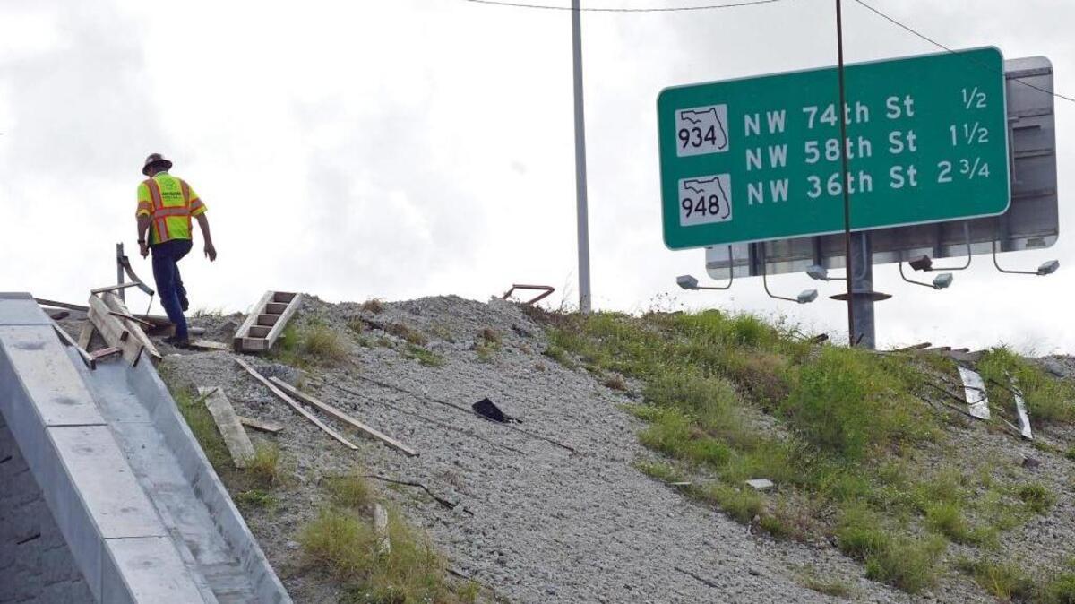 An investigator walks up to the site where a construction worker fell and eventually dies off the Palmetto Expressway near Okeechobee Road on Friday, Oct. 20, 2017.