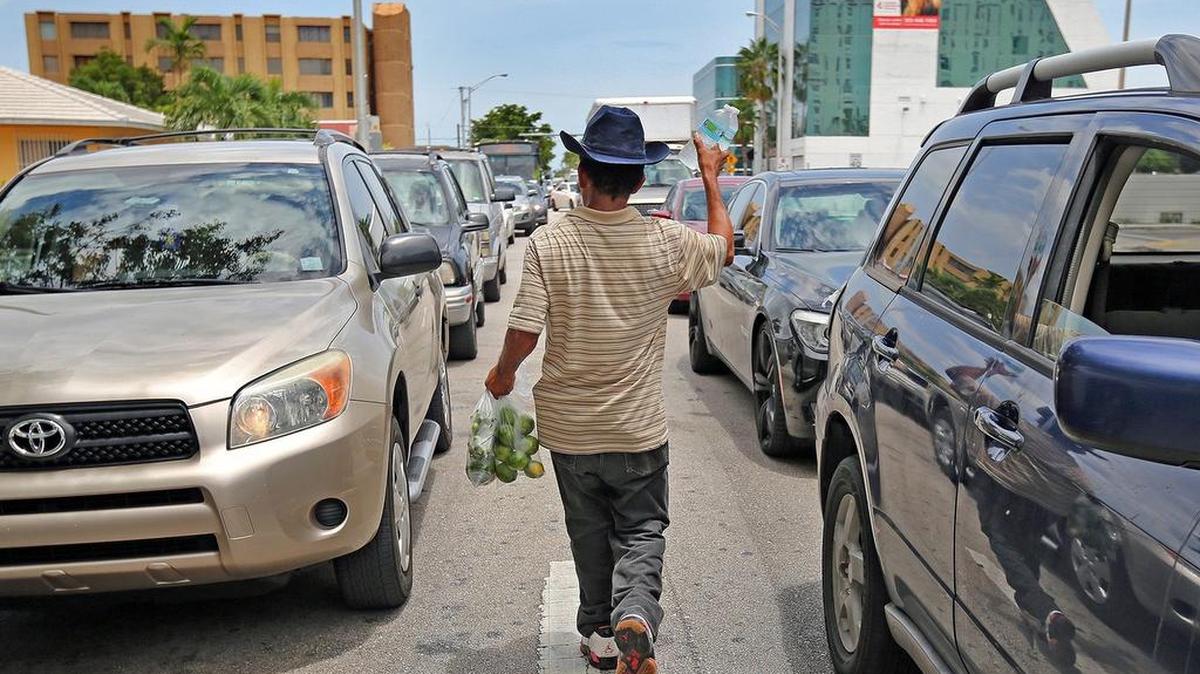 
A man selling fruit and water walks between the traffic jam at the corner of Flagler Street and Avenue LeJeune Road to sell his wares Thursday, July 30, 2015. While the traffic in Miami causes frustration to drivers, the vendors say sales are better when vehicles are stuck in traffic. 
