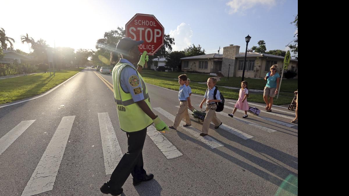 
Crossing Guard Berenise Monestime, a crossing guard for eight years, gets kids. Carlo Crousillat, Jason Smith, and Charlie Smith and Eva Crousillat safely cross NE 103rd Street at Fourth Avenue as they make their way to St. Rose of Lima Catholic School in Miami Shores Monday morning, August 19, 2013.
