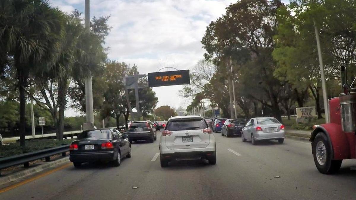 Traffic comes to stop beneath a street sign reminding drivers to ‘Keep safe distance. Stay Safe,’ as they head north on U.S. 1 past Veterans Wayside Park in Pinecrest during Thursday morning rush hour, April 20, 2017.
