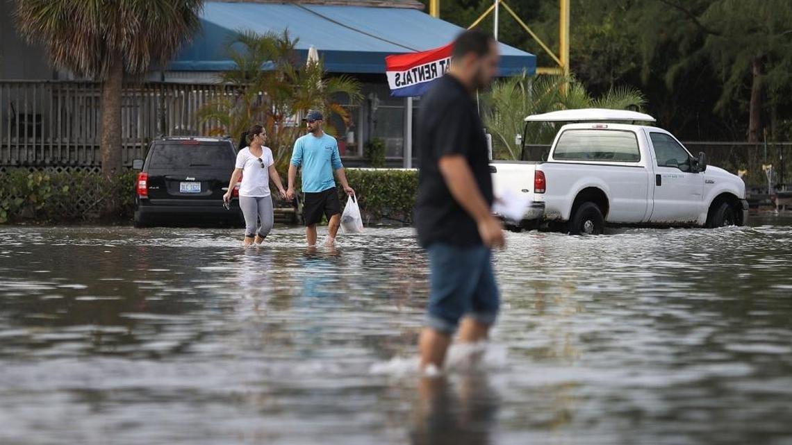 Yaneisy Duenas, left, and Ferando Sanudo walk through the flooded parking lot to their boat at the Haulover Marine Center on November 14, 2016 in North Miami, Florida.