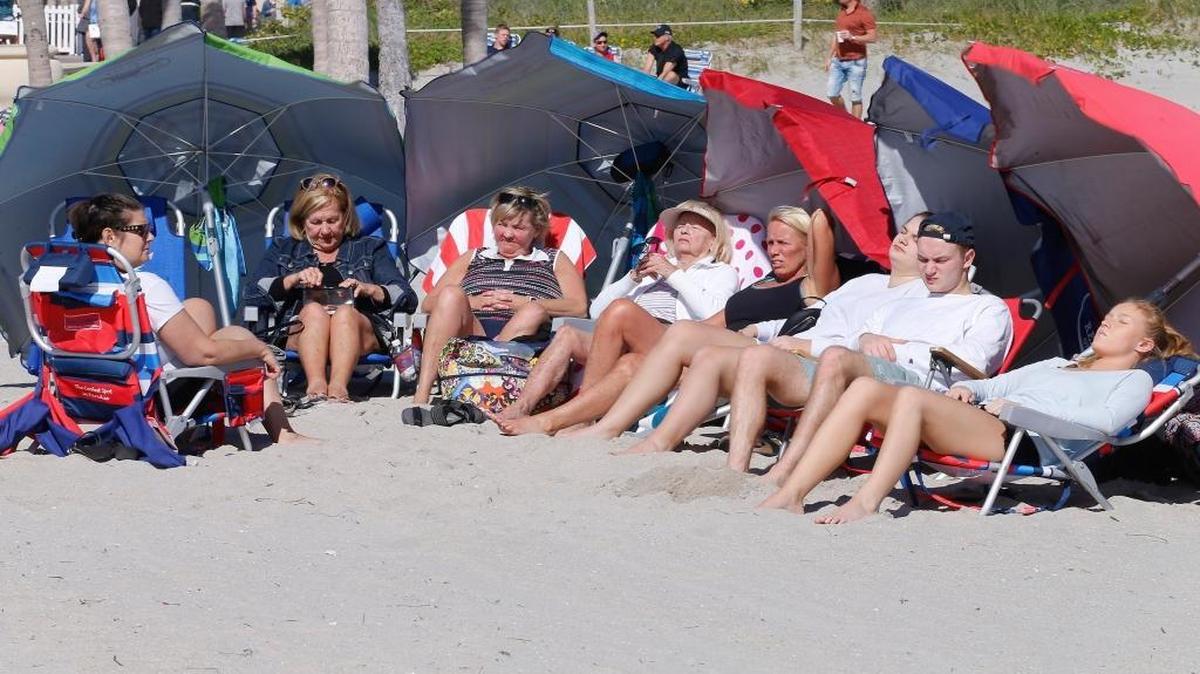 Canadian snowbirds bathe in the sunlight as the rough surf crashes against the shoreline of Hollywood beach in this January 2018 photo.