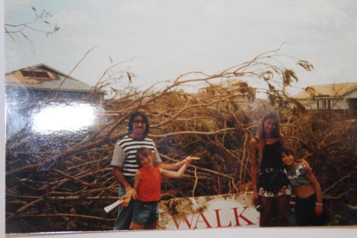 Lori Marcus and her husband, Alan, and their two daughters, Melissa, left, and Jennifer, stand outside their Country Walk home shortly after Hurricane Andrew demolished it in August 1992. The Country Walk sign blew into their yard.