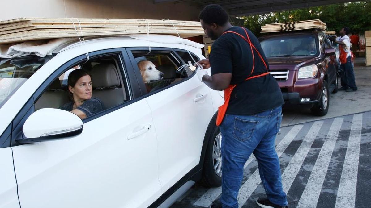 Beatriz Bustamante and her dog Simon wait as Qawrence Symonette secures sheets of plywood on her car at The Home Depot store in North Miami, Fla., Wednesday, Sept. 6, 2017. Florida residents are preparing for the possible landfall of Hurricane Irma, the most powerful Atlantic Ocean hurricane in recorded history.