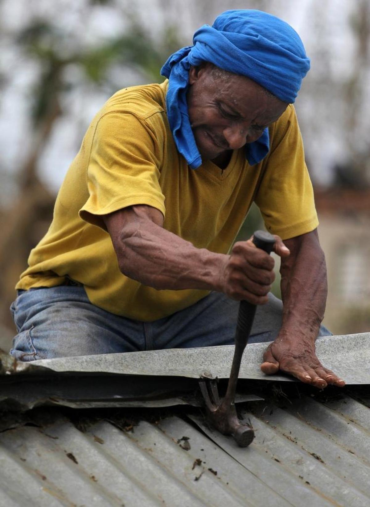 Jose Diaz Pisano, 67, remove the nails from the tin roof on his home on Friday as he salvages items to order to rebuild his house in Loiza, Puerto Rico, in the afternmath of Hurricane Maria.